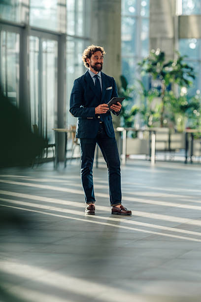 istock Smiling businessman holding digital tablet in modern office 2215787919