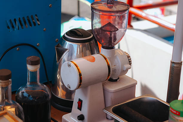 Close-up of a woman holding a vintage red enamel coffee pot at a flea market stall. The retro kitchenware, surrounded by antiques and collectibles, highlights nostalgic design and sustainable living.