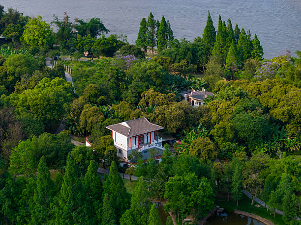 This aerial photograph captures a vibrant urban park adjacent to a serene waterfront, showcasing modern skyscrapers juxtaposed with lush greenery and recreational facilities. The visual style is realistic and detailed, offering a comprehensive view of city planning and natural integration. Potential uses include real estate marketing, urban development presentations, or environmental studies.