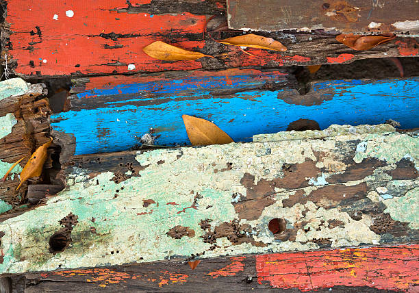 Horizontal close up flat lay of rustic eroded wood table top part with weathered peeling colorful paint revealing ageing process making abstract art