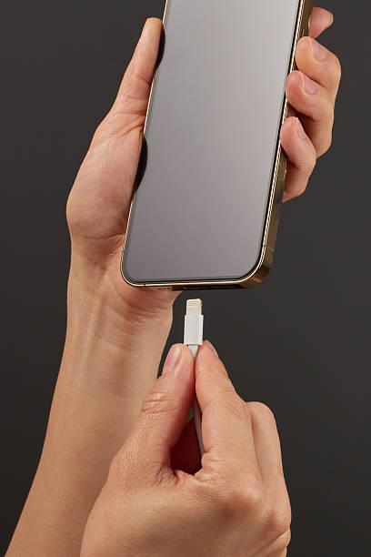 istock female hand plugging charger cord into smartphone 2215822976