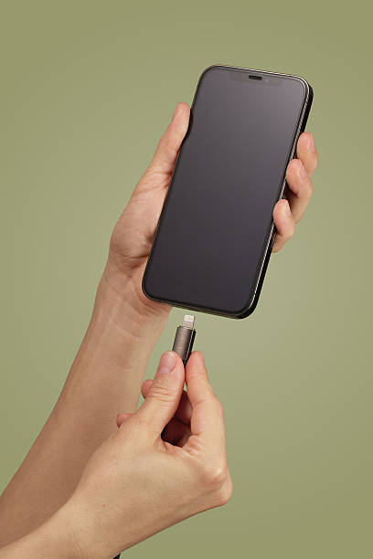 istock female hand plugging charger cord into smartphone 2215822985