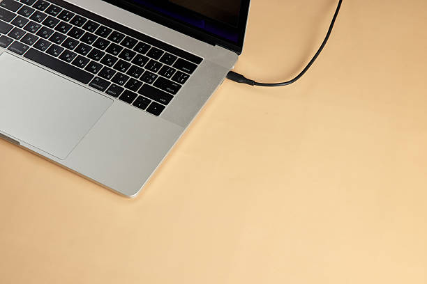 istock cable plugged in laptop on beige background, close-up 2215823010