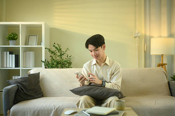 istock Smiling man checks messages or notifications on smartphone while seated in living room 2215823652