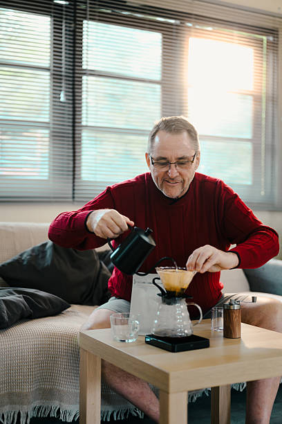 istock Happy elderly man carefully making pour-over coffee at home with a glass dripper and kettle 2215823718
