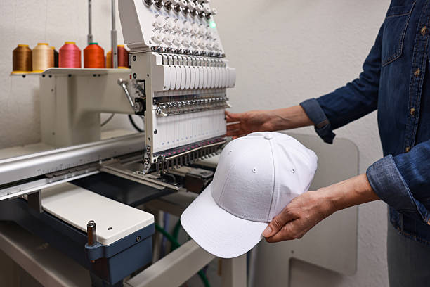 Woman with blank baseball cap for print using embroidery machine indoors, closeup