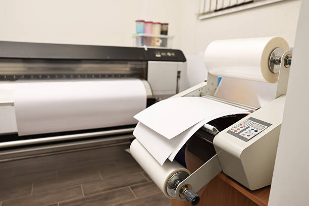 istock Modern roll laminator with paper on desk indoors. Printing house 2215824211