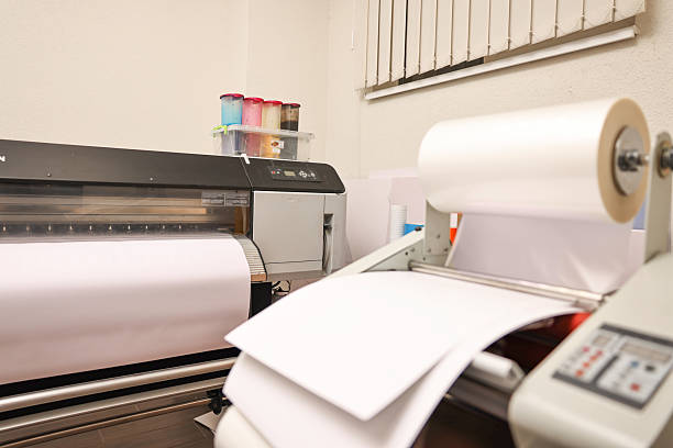 istock Wide-format printer and roll laminator with paper indoors, selective focus. Printing house 2215824236