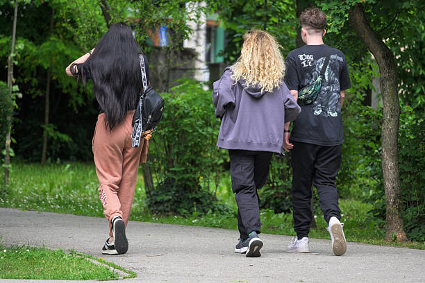 Young people, two girls and a boy, are walking in the park. Romania, Gorj. May, 17, 2025.