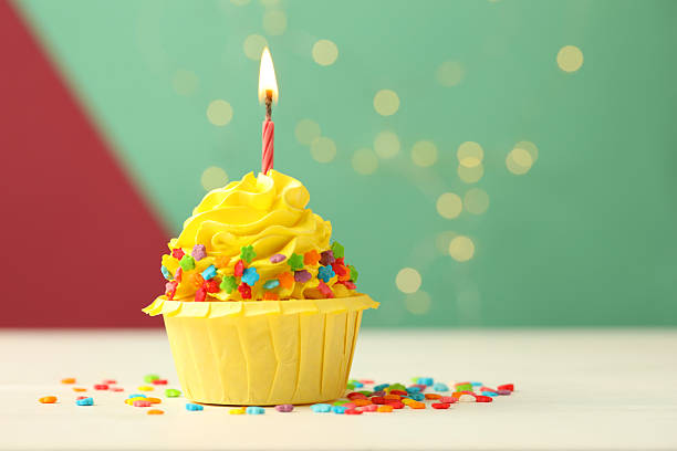 istock Tasty cupcake with burning candle on color background with blurred lights 2215824926