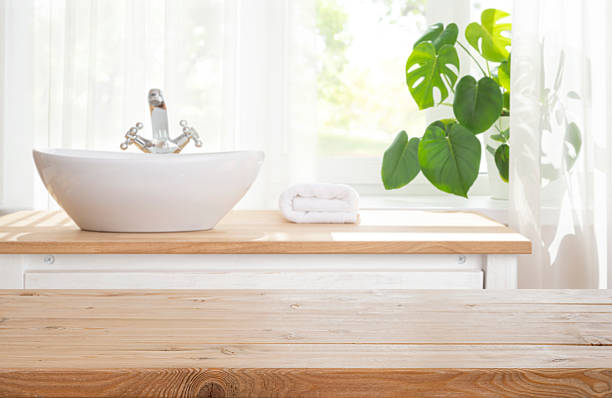 istock Wooden texture planks table top over blurred sink and folded spa towel in bathroom table with curtained window 2215828227