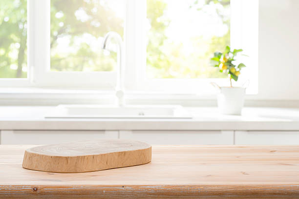 istock Wood podium board on wooden kitchen table over blurred sink against window interior background 2215828237
