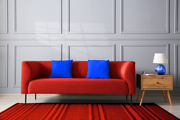 Vintage red leather sofa in colorful room interior with arc floor lamp, palm tree plant, and window.