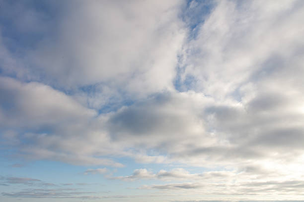 The sky is cloudy and the sun is shining through the clouds. The sky is blue and the clouds are white