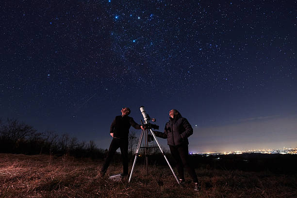 Amateur astronomers using telescope for watching stars, Moon, planets and other celestial objects from a field in nature.