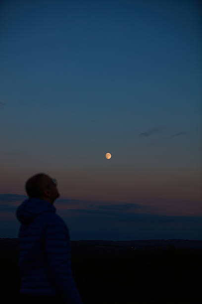 istock Silhouette of a man observing Moon, Milky Way stars, planets and other celestial objects from a dark countryside location. 2215832719