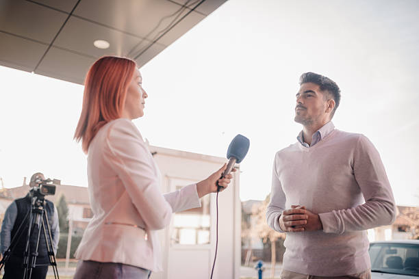 istock Journalist interviewing businessman holding microphone outdoors 2215832750