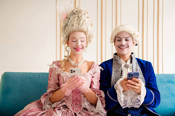 istock Royal-themed couple bonding in historical costumes using modern technology at home, blending aristocratic elegance with contemporary vibes 2215833559