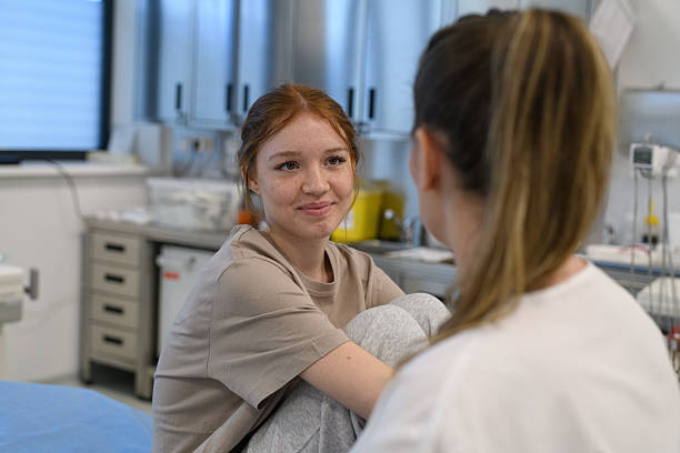 Teenage girl confiding in doctor about personal and health problems. stock photo