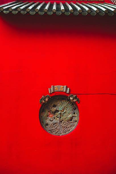 Traditional Chinese architectural detail with red wall and ornate circular carving, showcasing cultural artistry.