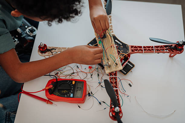 Young schoolboy assembling robotic kit and working with circuit board at home.