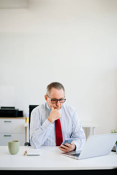 istock A mature businessman in red tie working on laptop at desk. Office scene with tech, thinking expression 2215836260