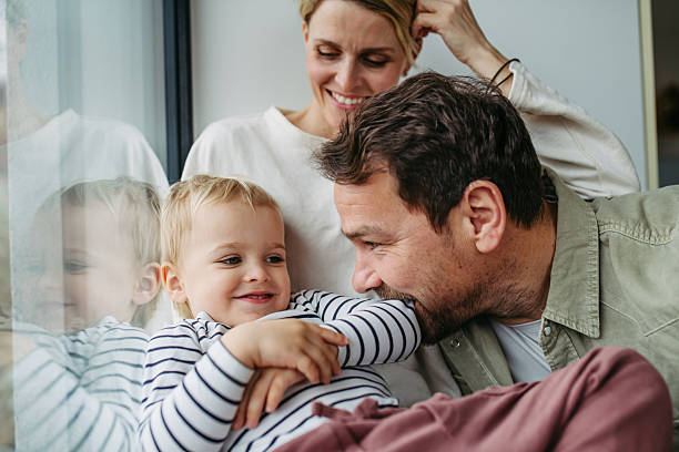 istock Parents playing with little son, sitting by window. 2215836892