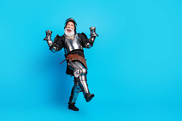 istock Elderly man in knight costume joyously posing on vibrant blue background 2215837671