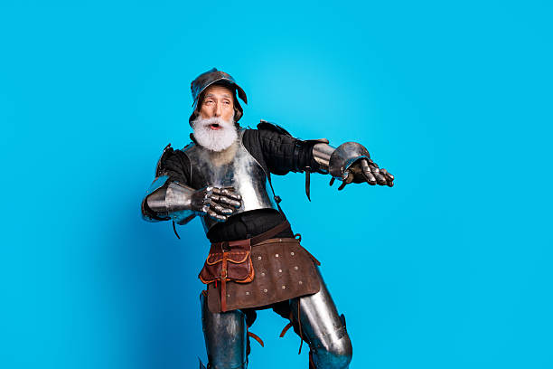 istock Senior knight in a steel armor costume posing humorously on a bright blue background 2215837677
