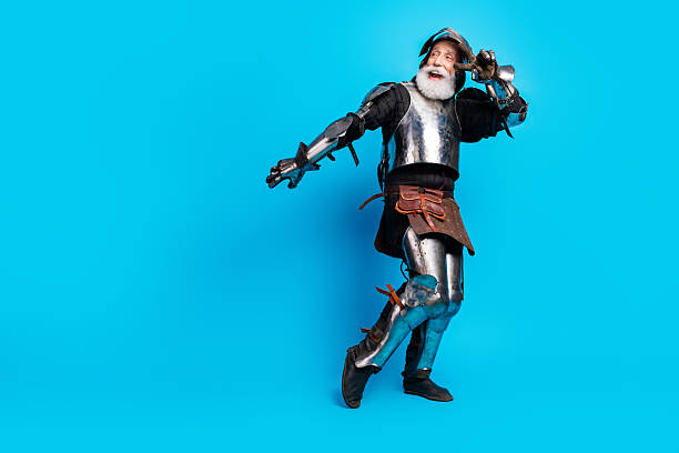 istock Playful aged knight posing in historical armor with a bright blue background 2215837681