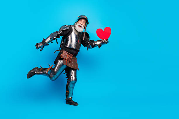 istock Elderly man dressed as a knight holding a heart against blue background 2215837719