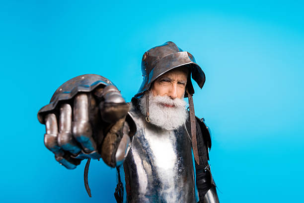 istock Elderly male knight in shining armor pointing defiantly against a bright blue background 2215837738