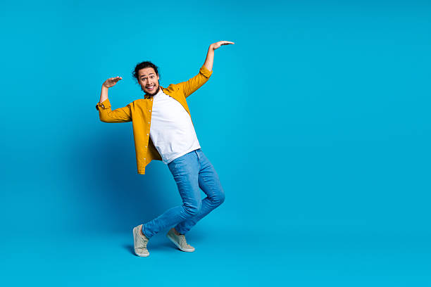 istock Energetic young man in a yellow shirt making expressive gestures on a vibrant blue background, showcasing positivity 2215839024