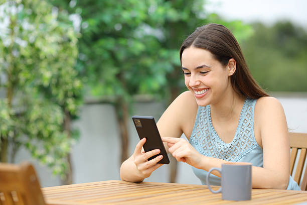istock Happy woman in a terrace browsing mobile phone content 2215841642