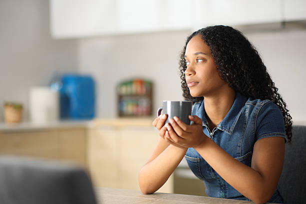 istock Pensive black woman in a kitchen drinking coffee 2215842076