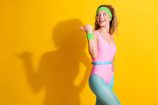 istock Energetic young sportswoman models vibrant retro activewear against a bright yellow backdrop 2215842245