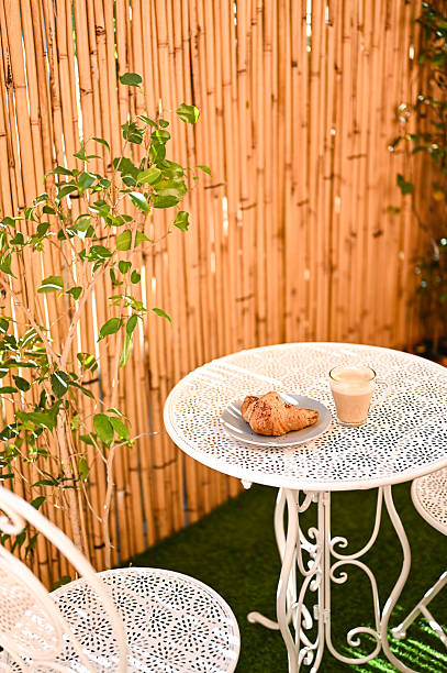 istock Cozy breakfast setting with croissant and cappuccino on a white table and chairs 2215842327
