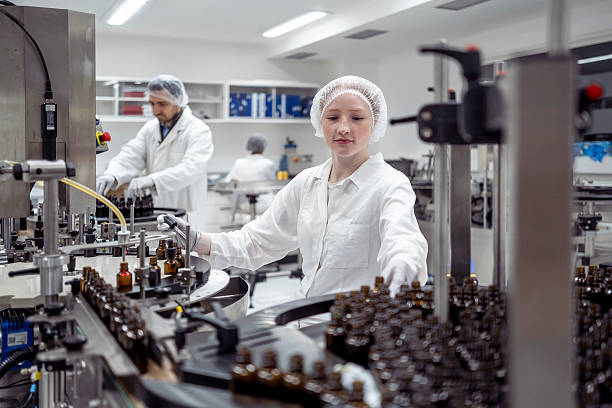 istock Young Female Lab Technician Packaging Bottles in Bright Industrial Lab with Precision 2215843114