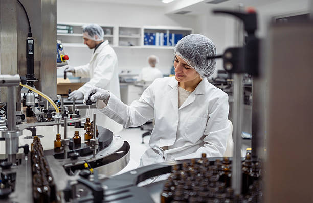 istock Mid Adult Female Lab Worker Packaging Products in Clean White Laboratory 2215843127