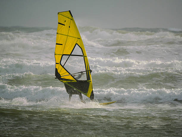 istock Water Sport Activity - Windsurfer Riding a Wave in Rough Sea on a Windy Day 2215843489