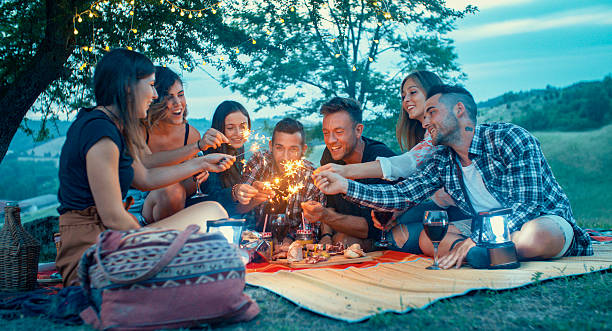 Friends celebrating with sparklers at a picnic under the trees stock photo