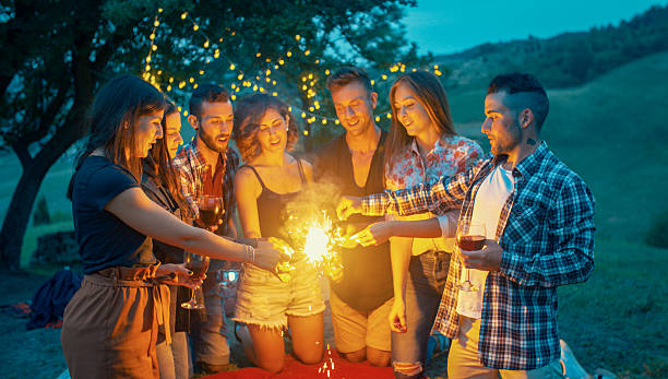 Friends lighting sparklers and drinking wine at night stock photo