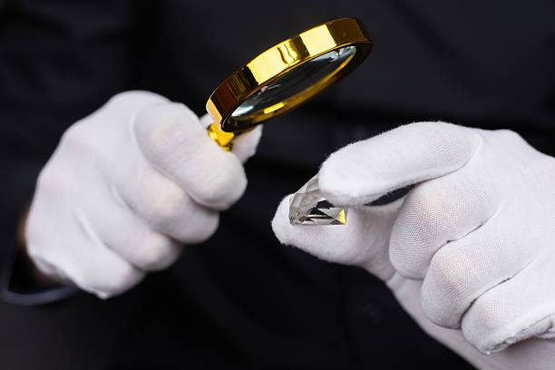 istock Man jeweller examines polished diamond through magnifier. Buyer checking diamond. 2215848122
