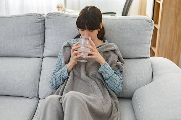 istock Woman self-medicating at home while resting on the couch 2215848475