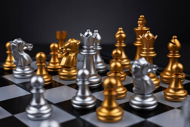 istock Gold and silver chess figures placed on wooden chessboard. Intellectual duel and tactical battle in business. 2215848491