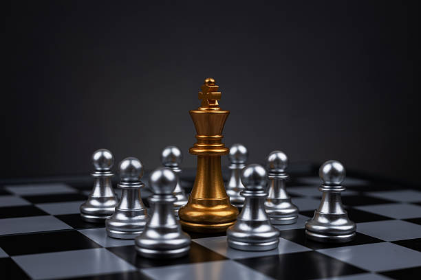 istock Golden chess king surrounded by silver pawns on chess board 2215848562