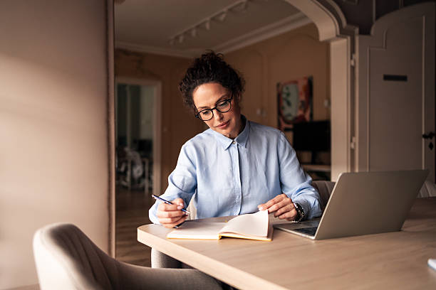 istock Professional Woman Writing Notes at Desk in Home Office Workspace 2215849569