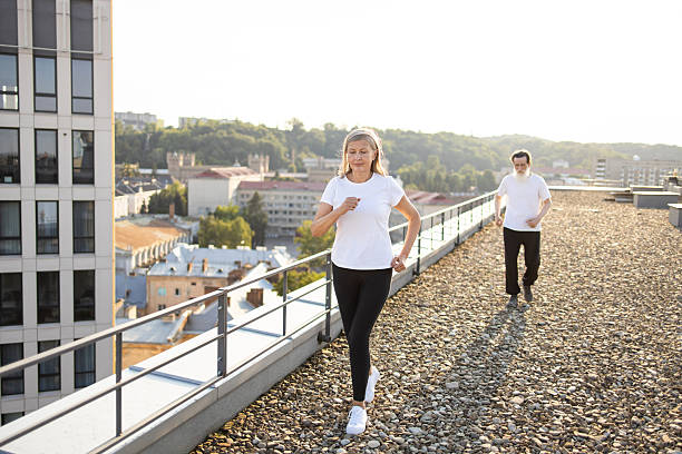 Young woman is jogging on pedestrian walkway at sunset.