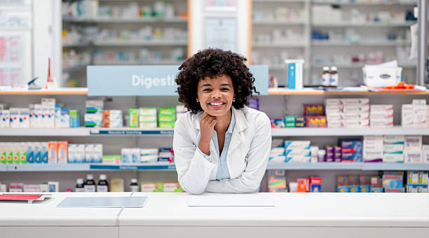 istock Smiling Pharmacist Standing Behind the Counter in a Well-Stocked Pharmacy 2215853101