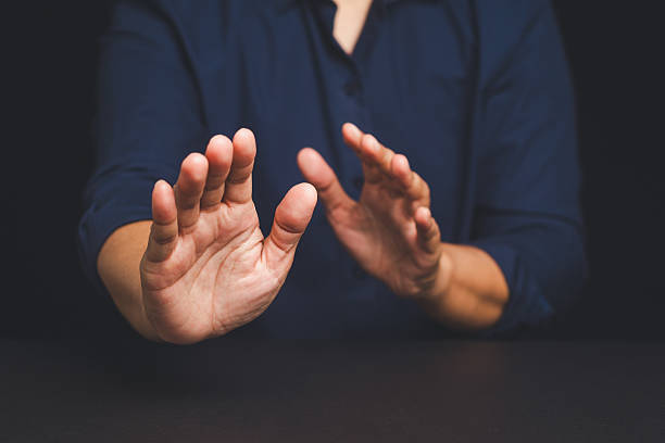 istock Man in navy shirt raising both hands in defensive stop gesture against dark background. 2215856580